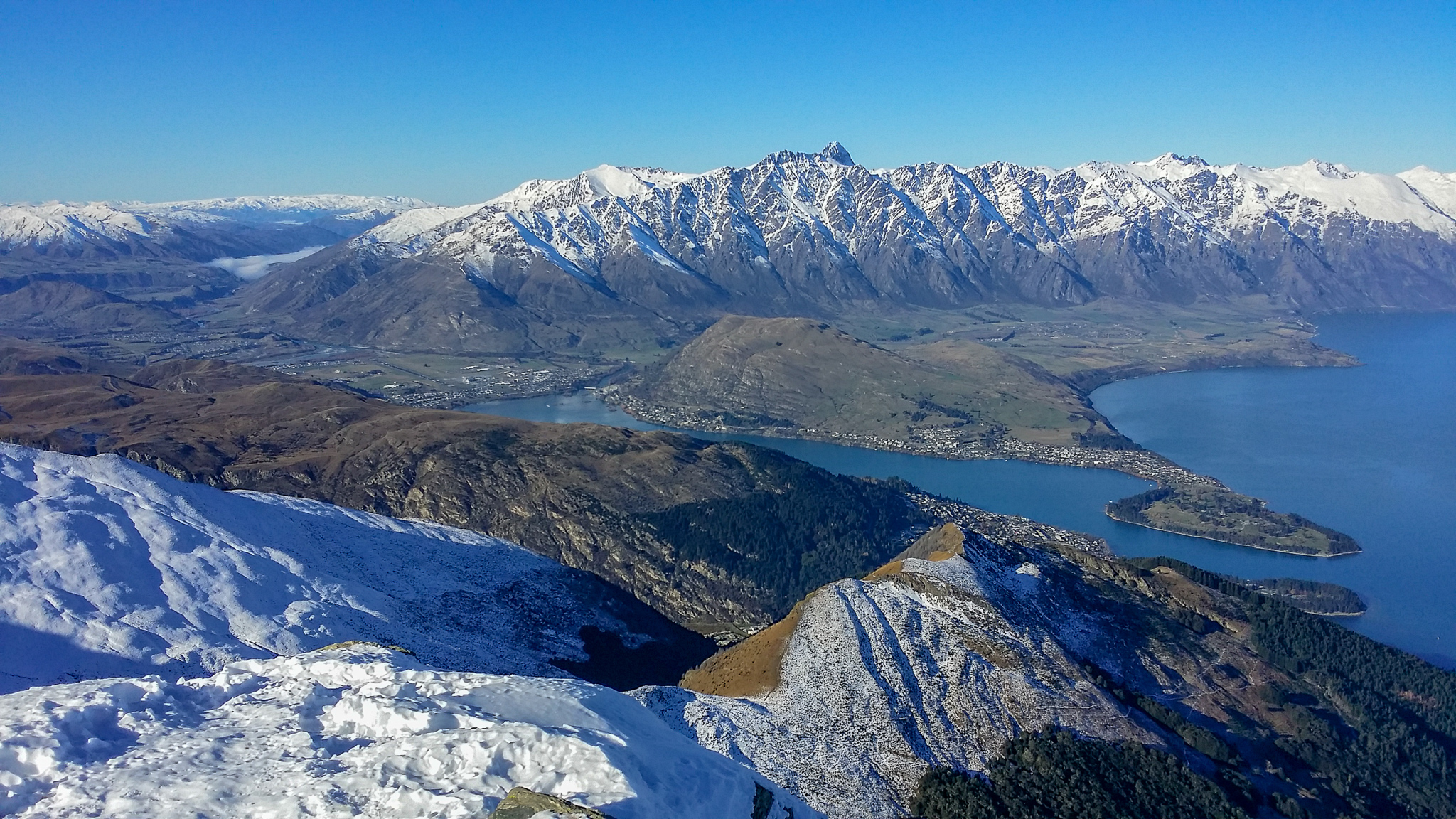 Photo from the summit of Ben Lomond summit in winter with the Remarkables and Lake Wakatipu in the background