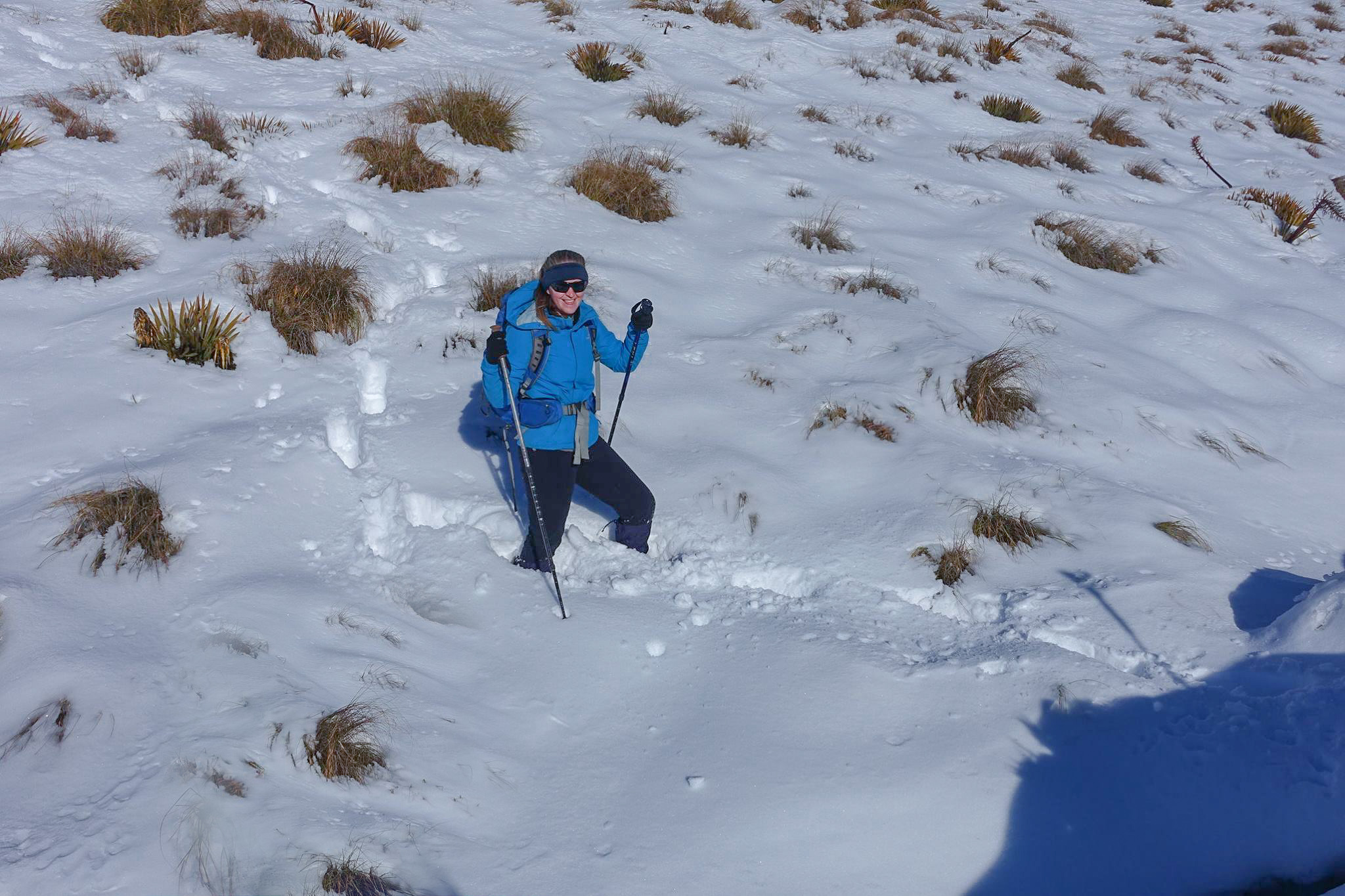 Female hiker standing in snow up to her knees in winter